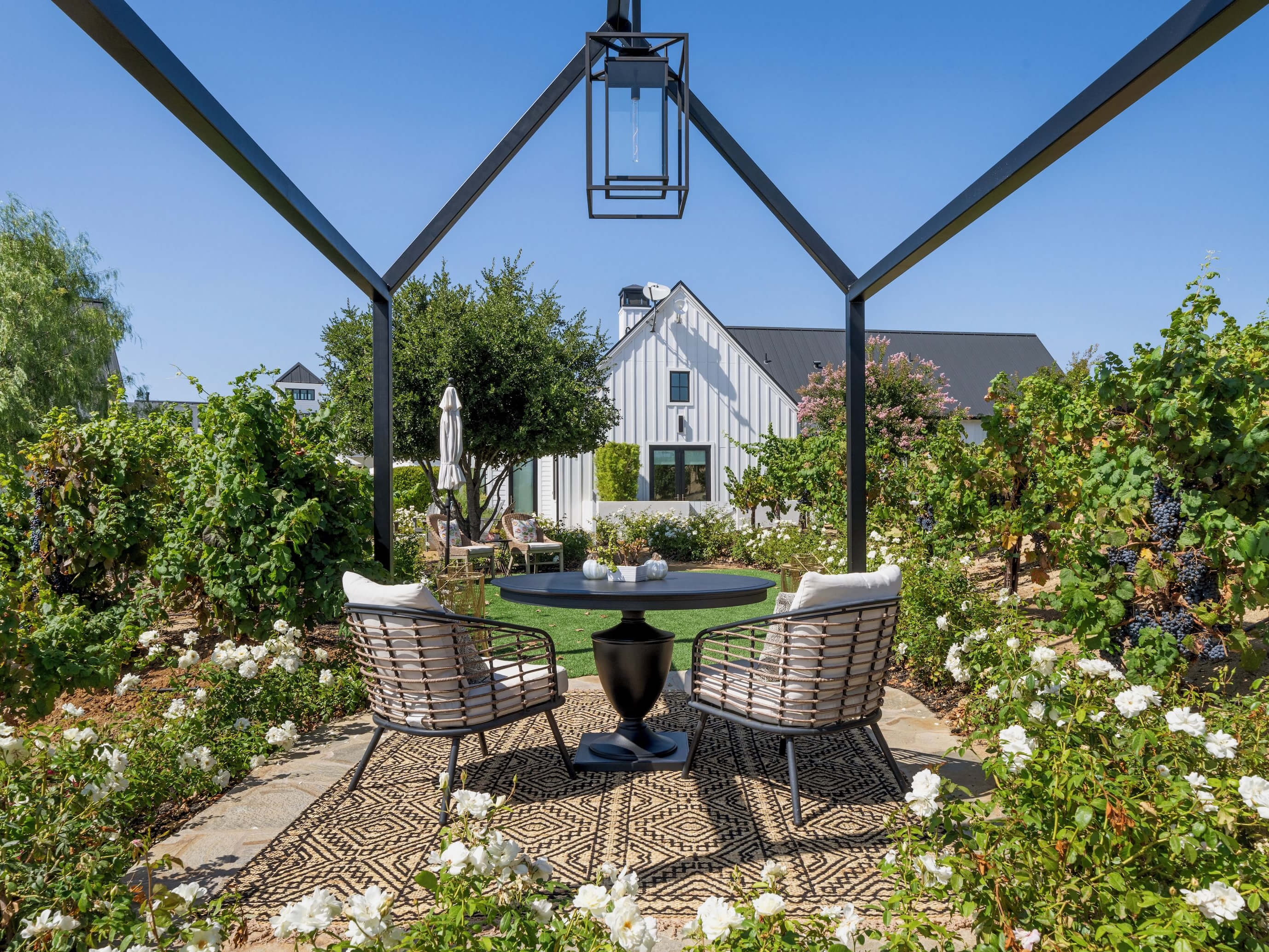 A small table in a garden courtyard facing a white, modern barn-style inn.