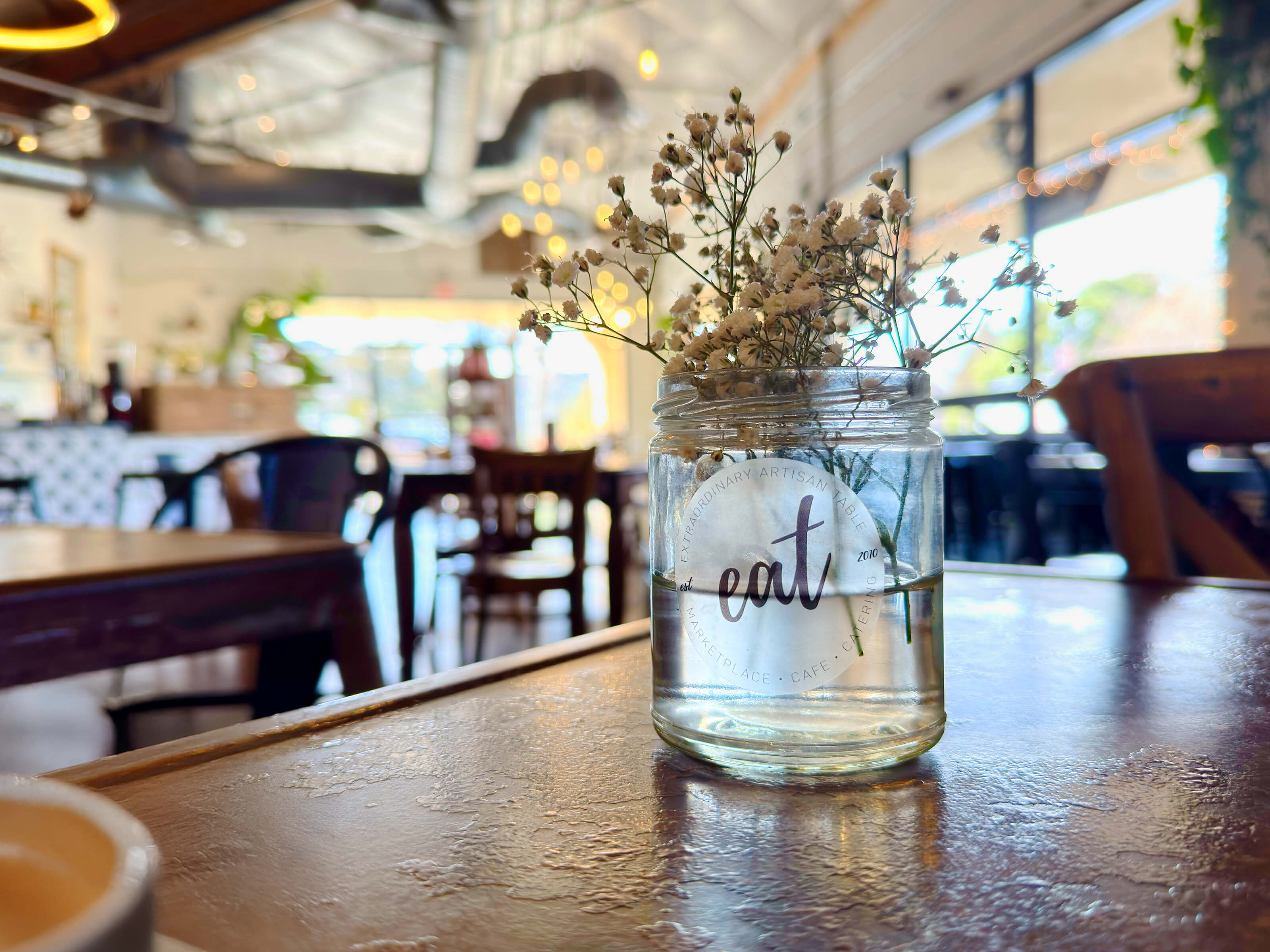 A table with a small jar with flowers and a label that reads "eat"